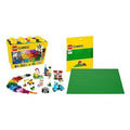 Bright yellow storage box filled with colorful Lego bricks, a green building baseplate, and instructions for creations.