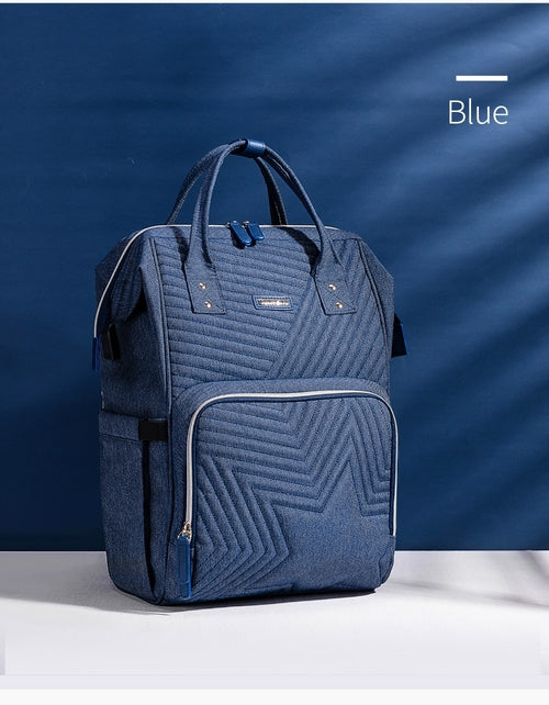 Quilted blue diaper bag backpack with a large front pocket, adjustable straps, and dual smooth zippers for easy access.