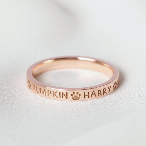 Personalized rose gold ring featuring the names "PUMPKIN" and "HARRY" with paw print accents.