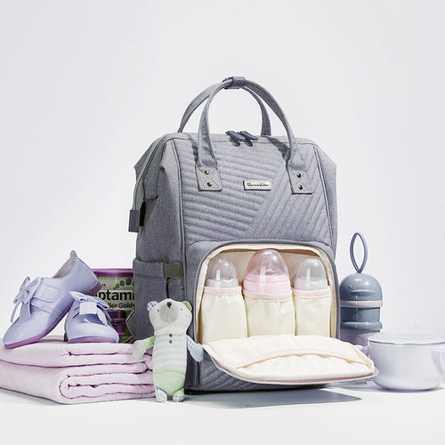 Gray Modern Quilted Diaper Bag Backpack with dual zippers and multiple compartments, displayed with baby items and toys.