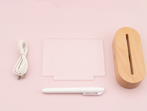 Wood table lamp with a USB connection, acrylic message board, and a white pen, set against a pink background.