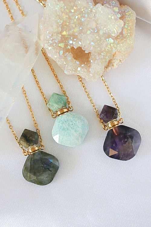 Three gold-plated necklaces featuring uniquely shaped natural crystal bottles: labradorite, amazonite, and amethyst.