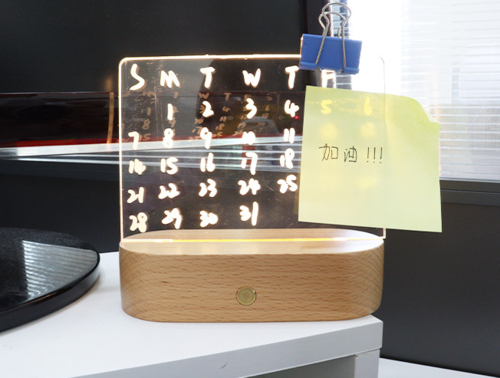 Wood table lamp with a wooden base and a clear acrylic message board displaying a calendar; features a sticky note.