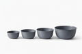 Four gray mixing bowls of varying sizes stacked, with a sleek, modern design and smooth matte finish.